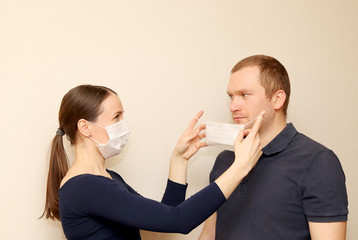 a woman puts a sterile medical mask on a man to protect against the virus