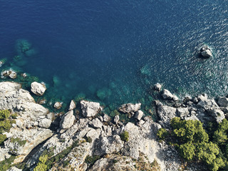 Sharp stones and rocks in the turquoise, blue sea. Drone aerial shot from above with white stone coast. Turkey