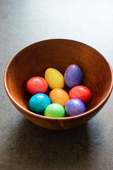 Fototapeta na wymiar Colorful painted Easter Eggs in a brown wooden bowl shot in window daylight