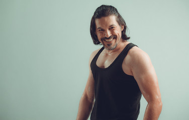 Fototapeta na wymiar Male bodybuilder wearing dark tanktop on ripped muscular torso in studio shot