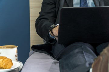 Home office concep with a man dressed in a suit in bed with a laptop