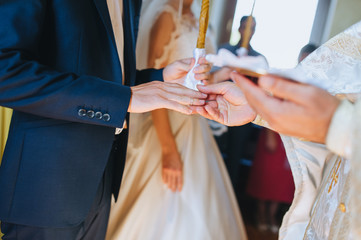 The priest holds a wedding ceremony in the church, rites and puts gold rings on the fingers of the...