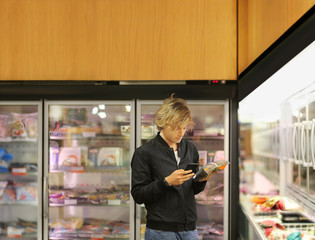 Man choosing frozen food from a supermarket freezer	