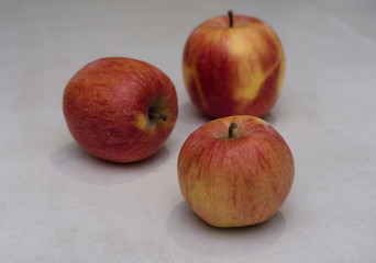Three red apples on a white background, apples on a white table, fresh apples in the kitchen