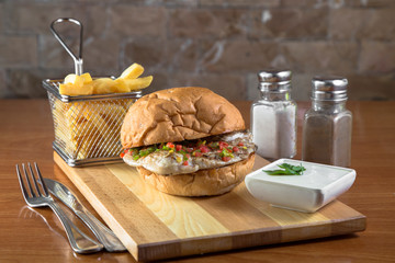 Chicken fillet between buns on board with pommes frites