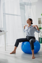 Obraz premium beautiful happy businesswoman exercising on fitness balls in office