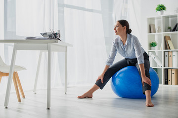 smiling businesswoman exercising on fitness balls in office