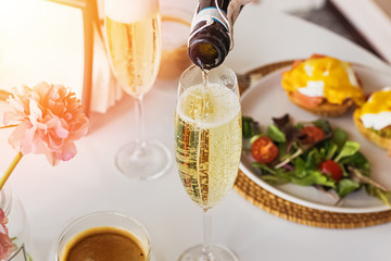 Pouring prosecco sparkling wine in a glass on sunday brunch - obrazy, fototapety, plakaty