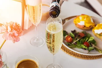 Fotobehang Pouring prosecco sparkling wine in a glass on sunday brunch © Diana Vyshniakova