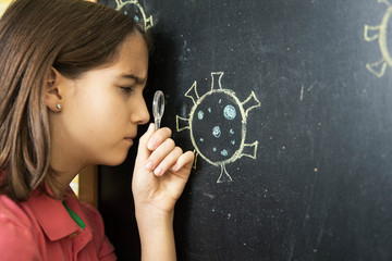 Obraz premium Girl looking at the drawing of a coronavirus with the magnifying glass