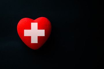 Red heart with cross sign on the black background