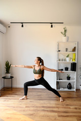 Young positive woman is practicing yoga at home