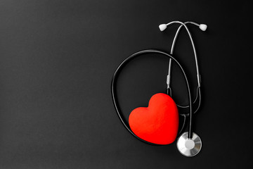 Red heart and stethoscope on Black paper. Flat lay essential items for doctor using treat and care...