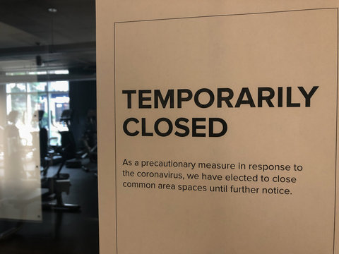Temporarily closed gym sign on door.