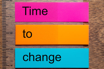 Three bookmark stickers with the words time to change, on a dark natural wooden table