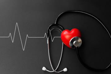 Red heart and stethoscope on Black paper. Flat lay essential items for doctor using treat and care...
