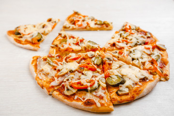 Italian pizza with bacon and pickles, mushrooms, capers and Parmesan cheese. Side view, top view. On a light table. Space for text