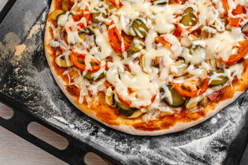 Italian pizza with bacon and pickles, mushrooms, capers and Parmesan cheese. Side view, top view. On a light table. Space for text