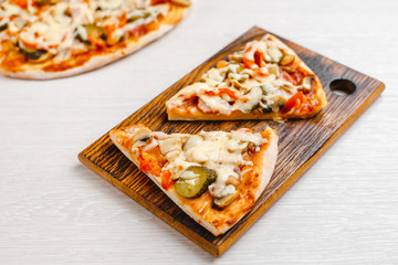 Italian pizza with bacon and pickles, mushrooms, capers and Parmesan cheese. Side view, top view. On a light table. Space for text