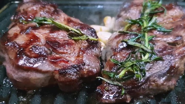 Close-up of steaks of marbled beef on the grill. Rosemary and garlic