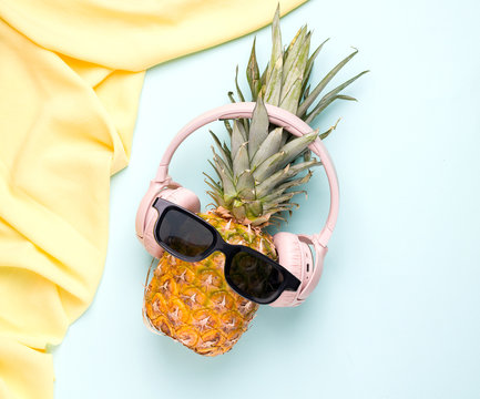 Summer concept with tropical pineapple fruit in sunglasses and headphones on a blue background. - Powered by Adobe