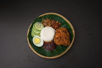 Nasi Lemak-Malaysian cuisine. A fragrant rice dish cooked in coconut milk and pandan leaf commonly found in Malaysia. Served with sambal, anchovies, peanut and cucumber.