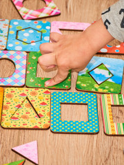 Kid's hands with Montesori pazzls close-up. Montesori wooden game for the development of children. Child development retardation.