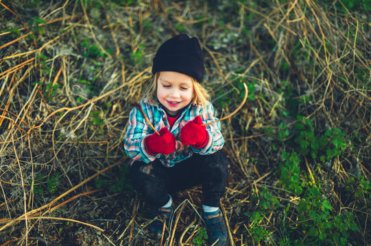 Preschooler sitting in field an dholding sticks