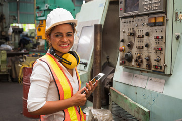Female industrial worker working and checking machine in a large industrial factory with many equipment.