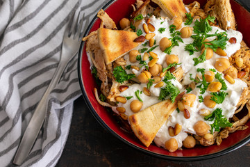 Lebanese Chicken Fatteh: A bowl of shredded chicken, toasted pita, and garbanzo beans in a garlic...