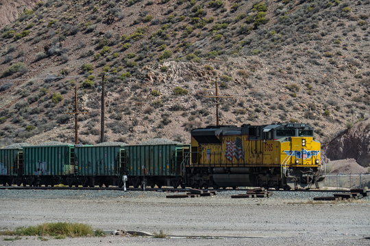 Caliente, Nevada/USA - 29 September 2018: Yellow american type fright train passing a village