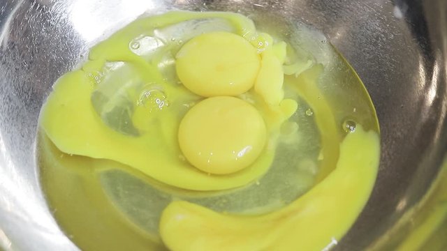 Breaking eggs in a matel bowl. Fresh organic eggs falling into bowl. Preparing ingredients for baking.