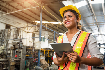 Female industrial worker working and checking machine in a large industrial factory with many...