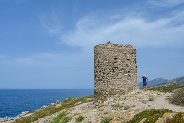 Young man near the genoese tower at Punta Spano amongst the maquis and rocks, Balagne region of...