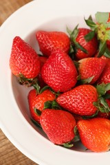 Juicy strawberries in a white plate on the table