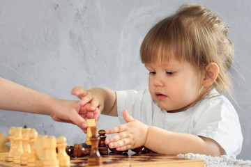 a little girl plays chess in her room in self-isolation