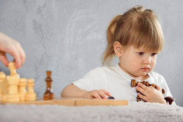 a little girl plays chess in her room in self-isolation
