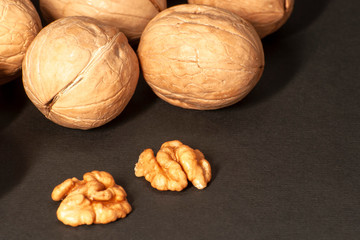 Whole and chopped walnuts on a black background. Place for text. Copy space