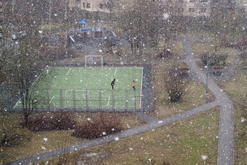 A teacher teaches a student football in winter.