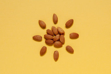 Roasted almonds laid out in the form of the sun on a yellow background. view from above . place for text. copy space