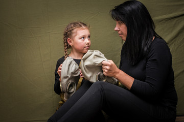 A woman shows a girl how to use a gas mask correctly. Mom teaches her daughter to put a gas mask on...