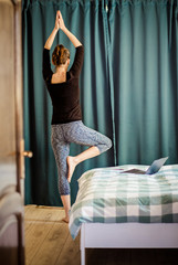 woman in a yoga pose in bedroom staying fit and mentally healthy at home