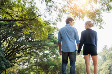 Young lovers walk hand in hand in the park Romanticly. On a relaxing holiday