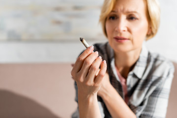 selective focus of mature woman holding joint with legal marijuana
