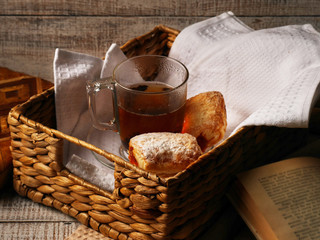 Tea and sweet cookies in a wicker tray on white wooden background. Open Book near the afteroon tea