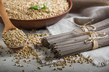 Rural still-life - traditional japanese soba noodles made of buckwheat flour and the peeled groats of buckwheat, on the background of burlap, closeup with selective focus