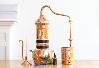 Distilling apparatus alembic with esential oil flowers at the wooden table. - obrazy, fototapety, plakaty
