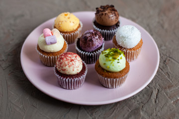 Tasty mini cupcakes on concrete background top view