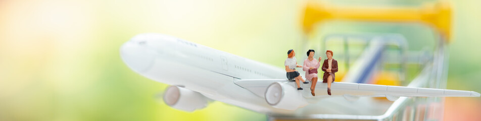 Miniature people: Business team sitting on airplane with copy space using as background business cover page concept.