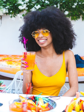 Vertical Portrait Of Beautiful African American Smiling Girl With Afro Hairstyle Drinking Cocktail And Eating Fruit, Vertical Image